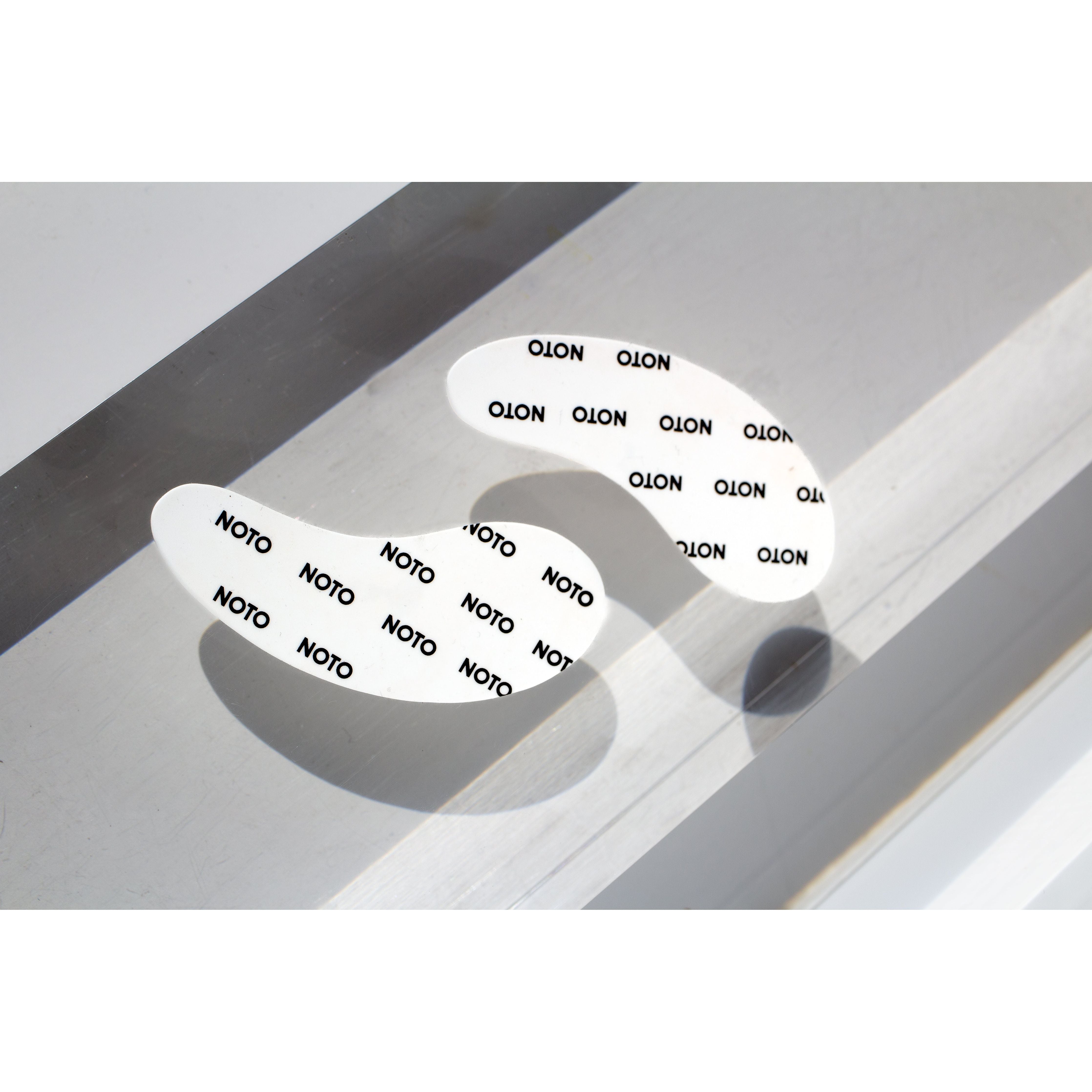 eye patches sitting on a white background with the noto logo written on them 